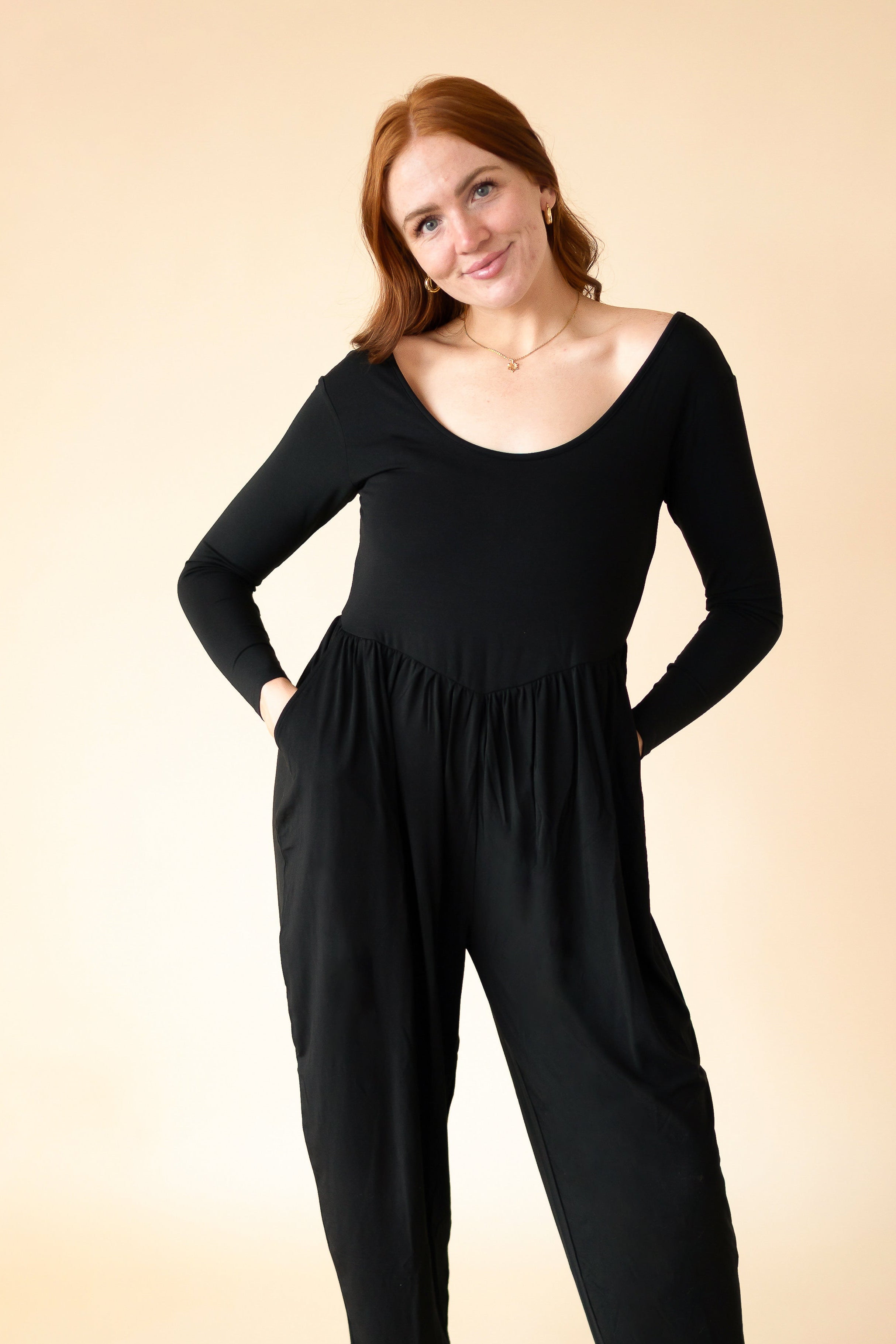 A woman wears a black long-sleeve romper with a scoop neckline.