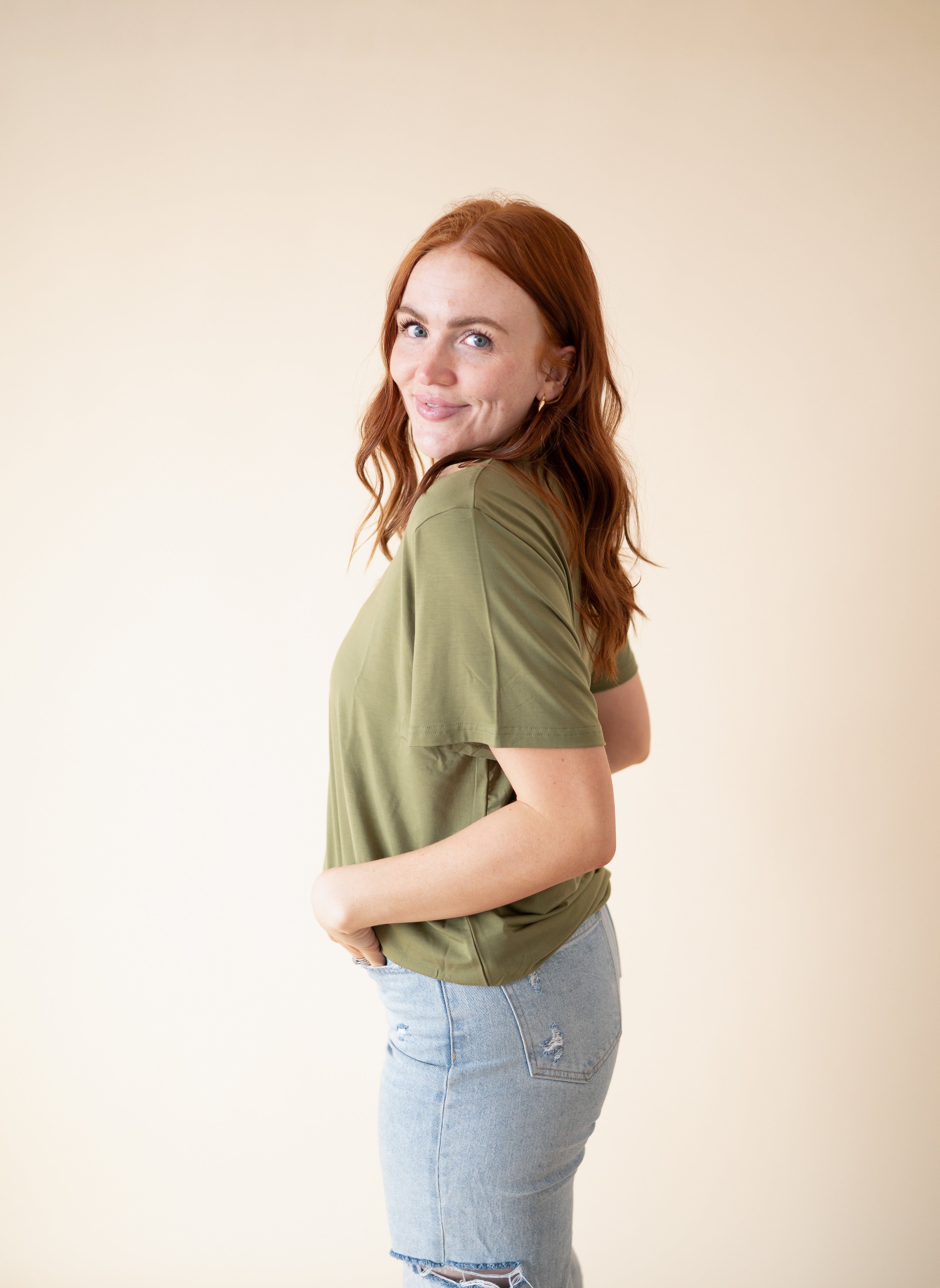 Oversized olive green tencel modal tee with distressed light wash denim jeans.