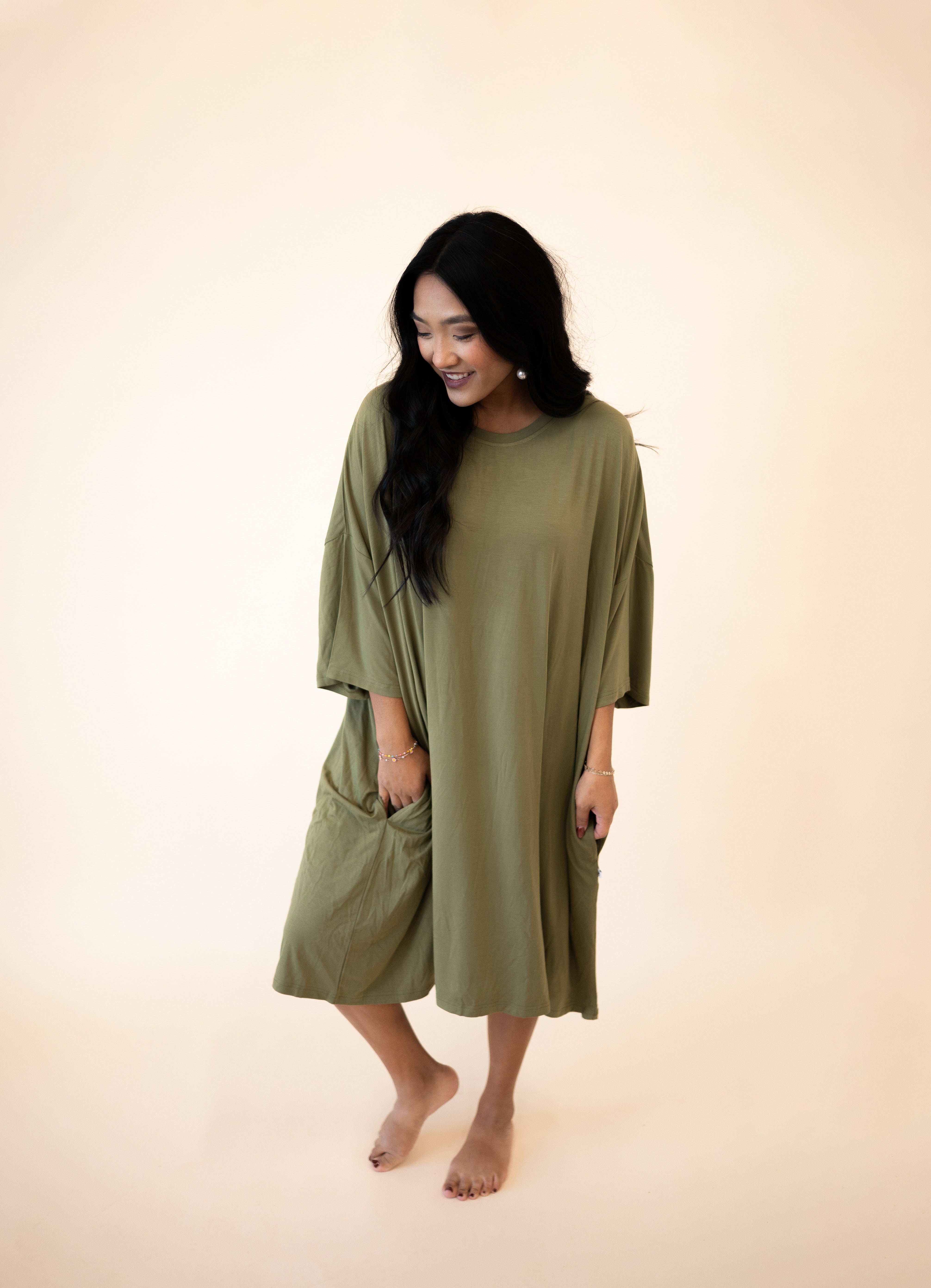 A woman wears an olive green Tencel Modal mega sleep tee with pockets.