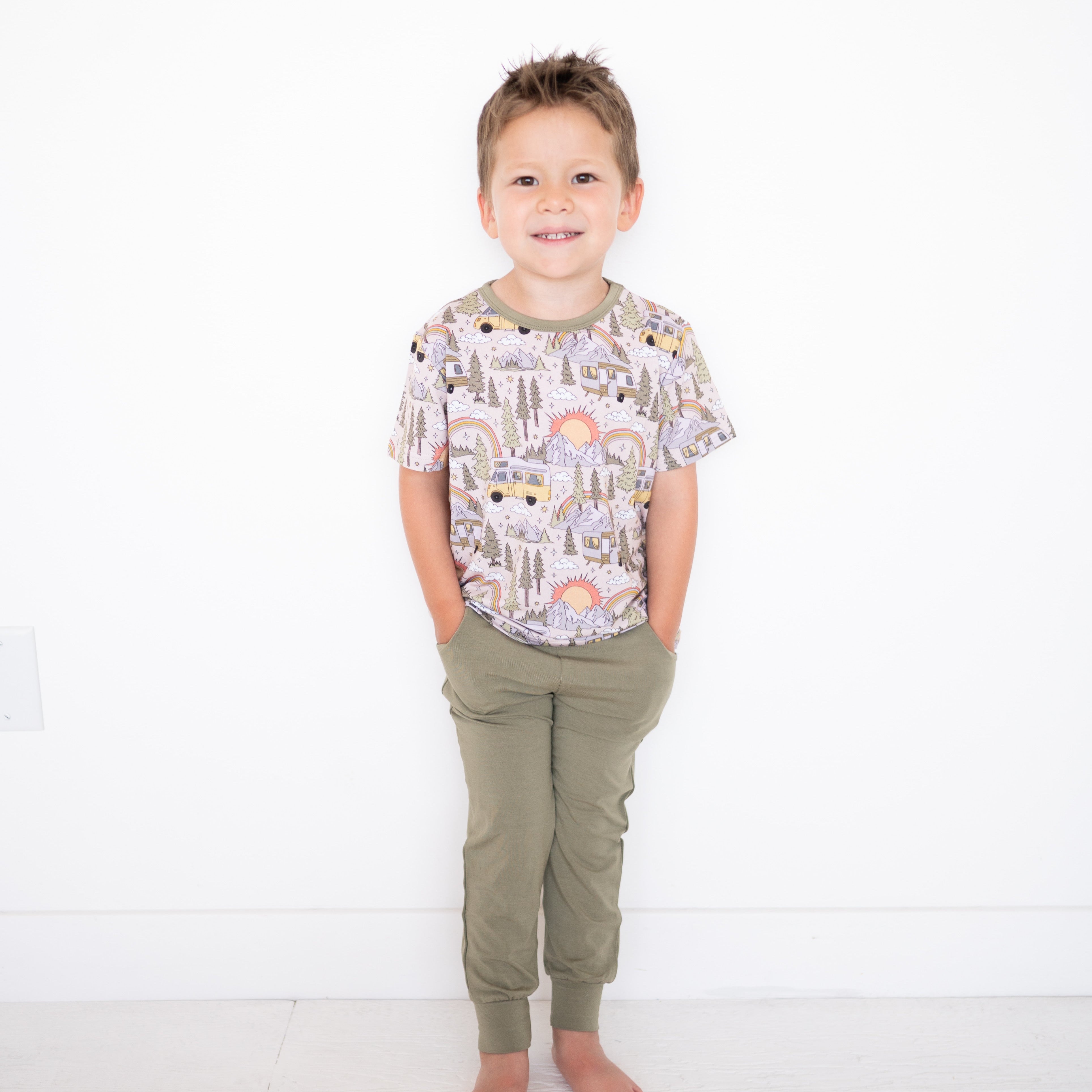Child wearing a patterned shirt and green pants on a white background