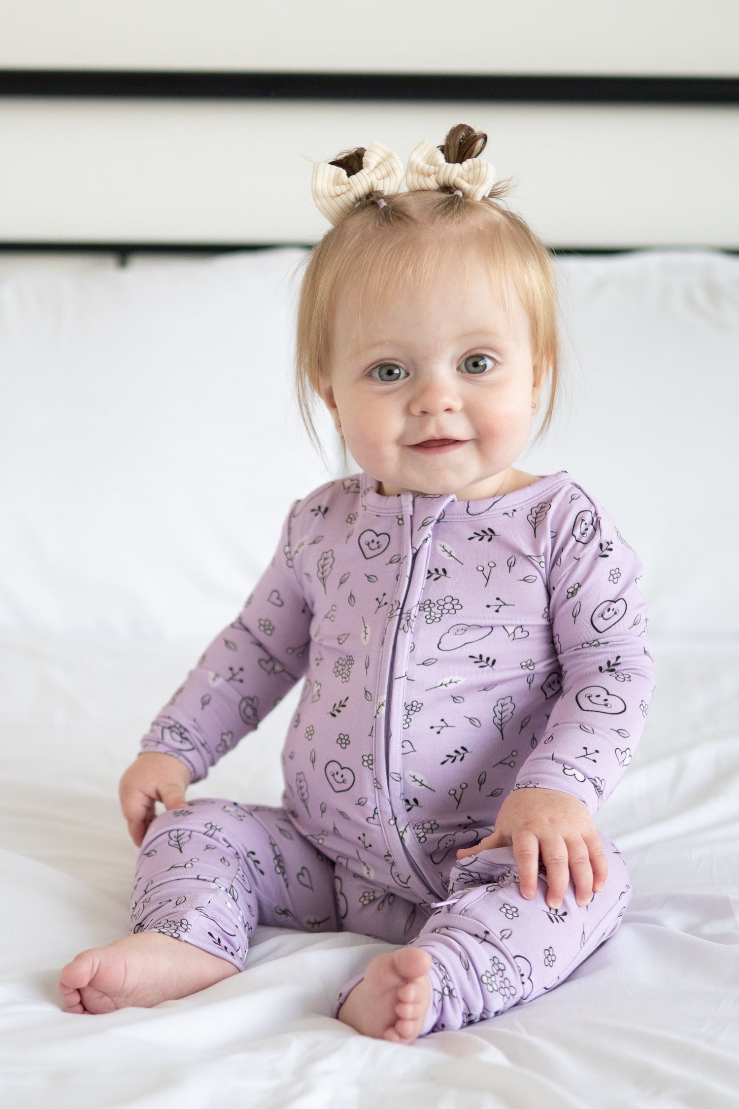 A baby girl wearing a lilac bamboo pajama set with a doodle print.