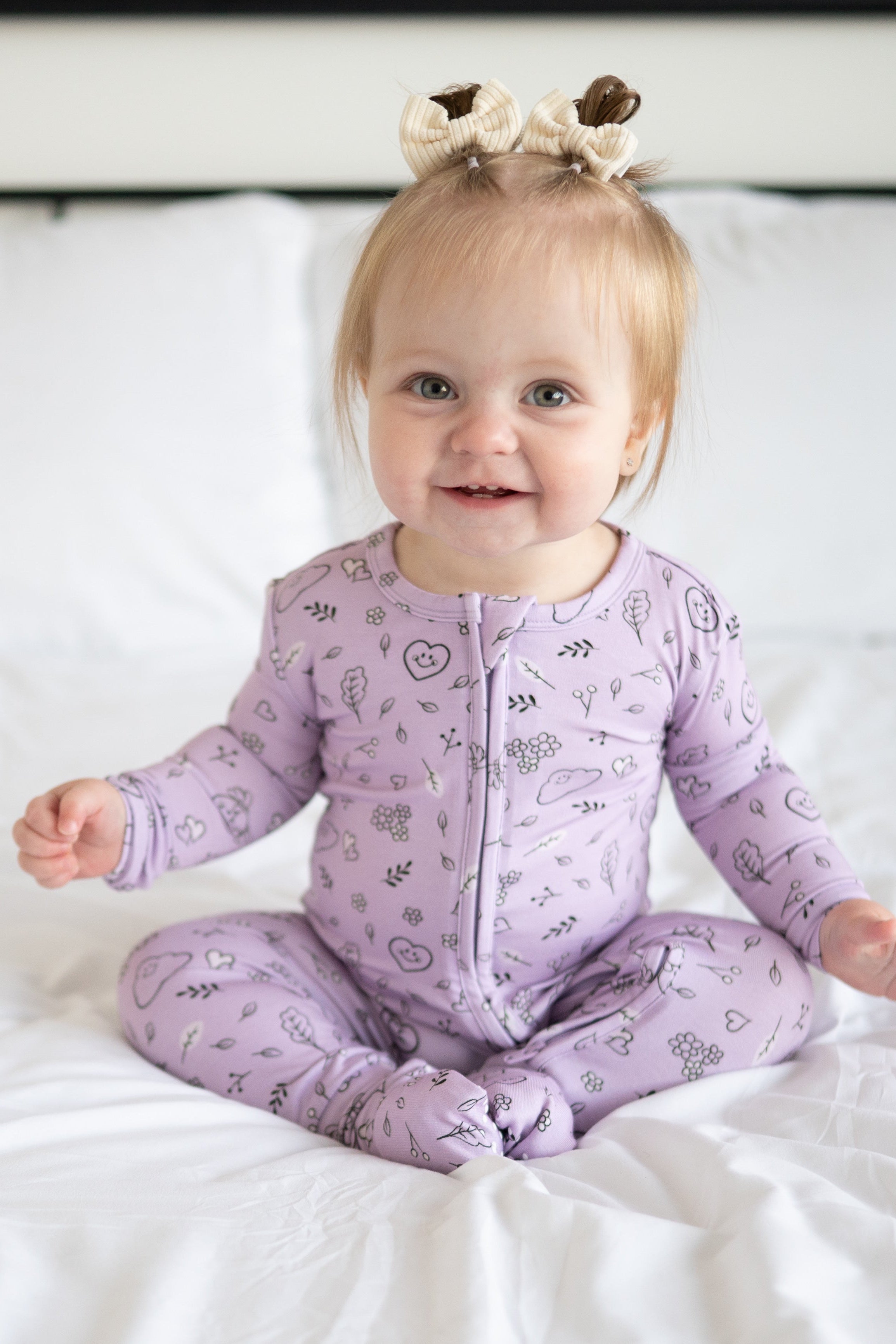 A baby girl wearing a lilac bamboo pajama set with a doodle print.