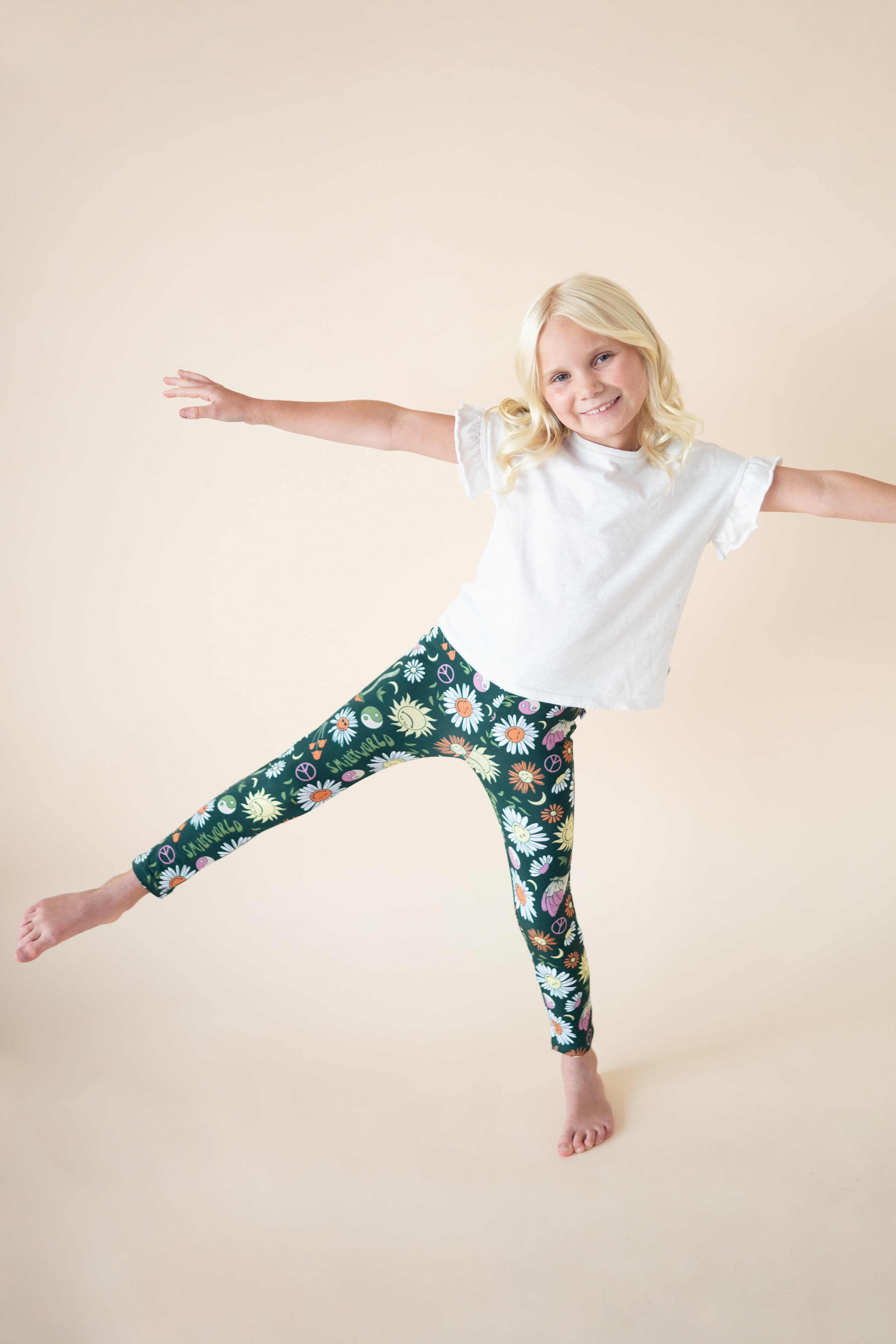 Girl wearing green leggings with a floral and smiley face print.