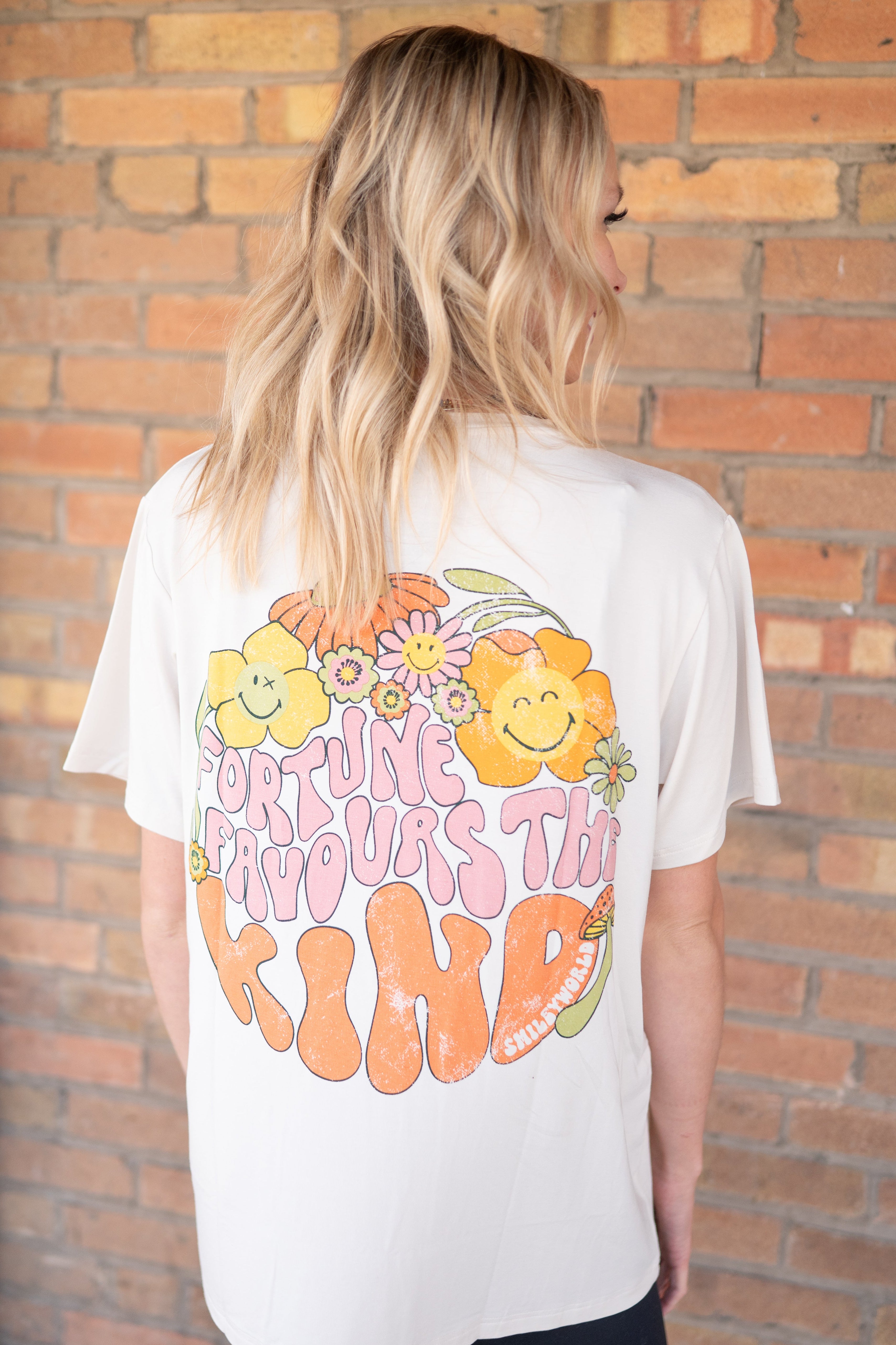 Oversized white t-shirt with a colorful smiley flower graphic and text.