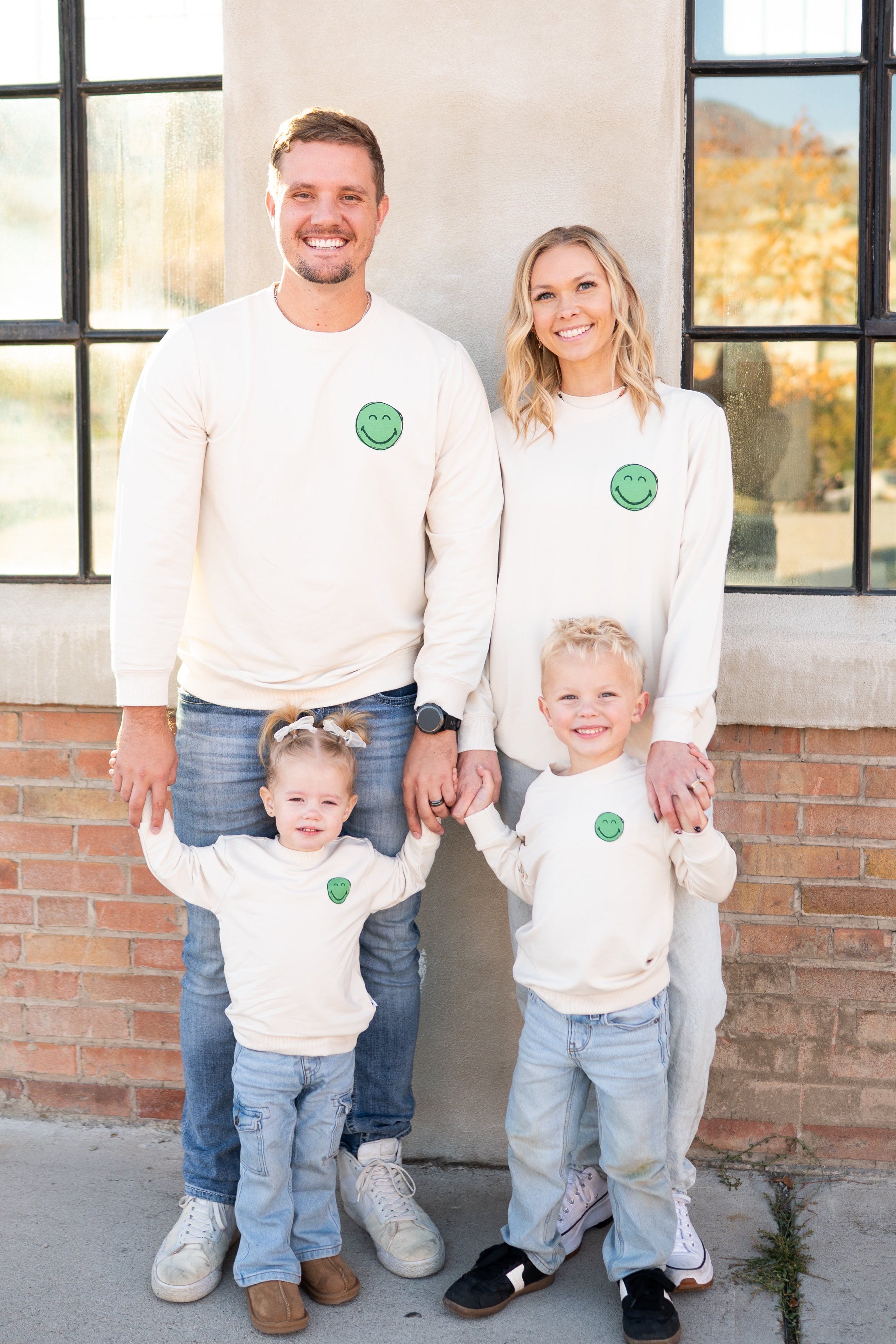 Family wearing matching cream SmileyWorld crewnecks.