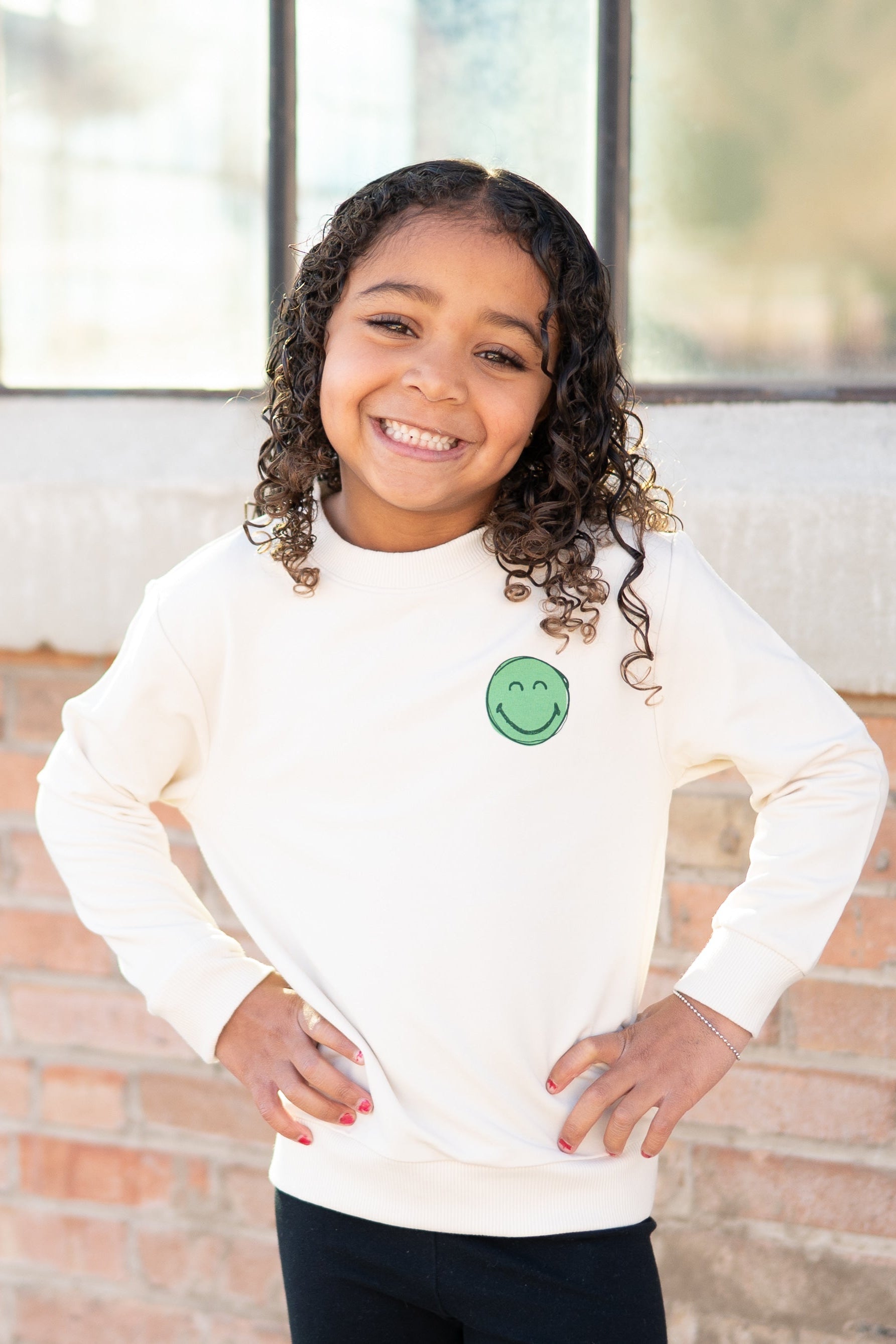 Cream crewneck sweatshirt with a green smiley face graphic.