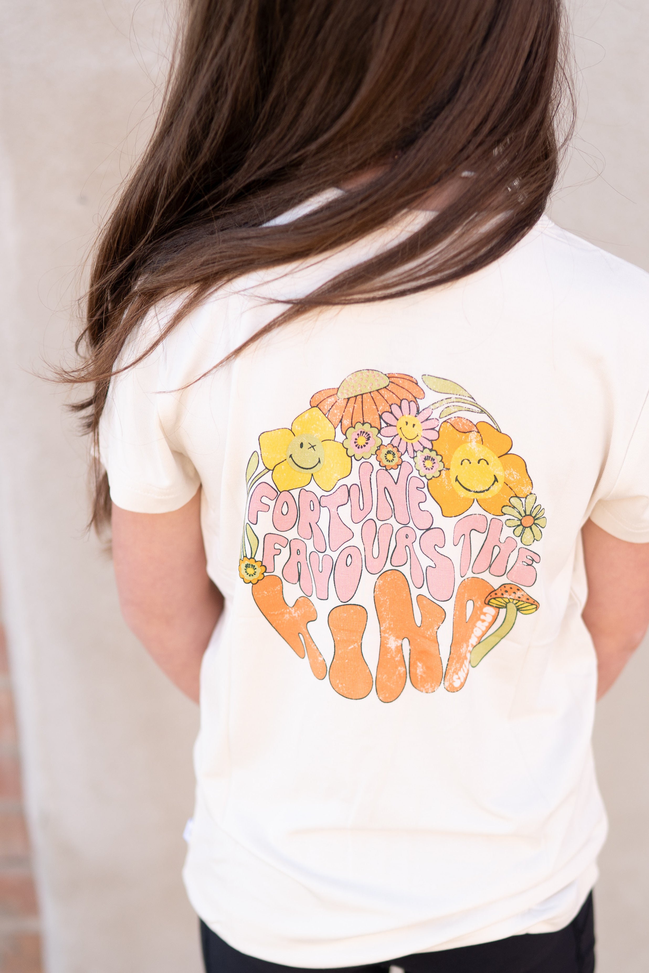 Cream t-shirt with a retro graphic of flowers, mushrooms, and the words "Fortune Favors The Kind".