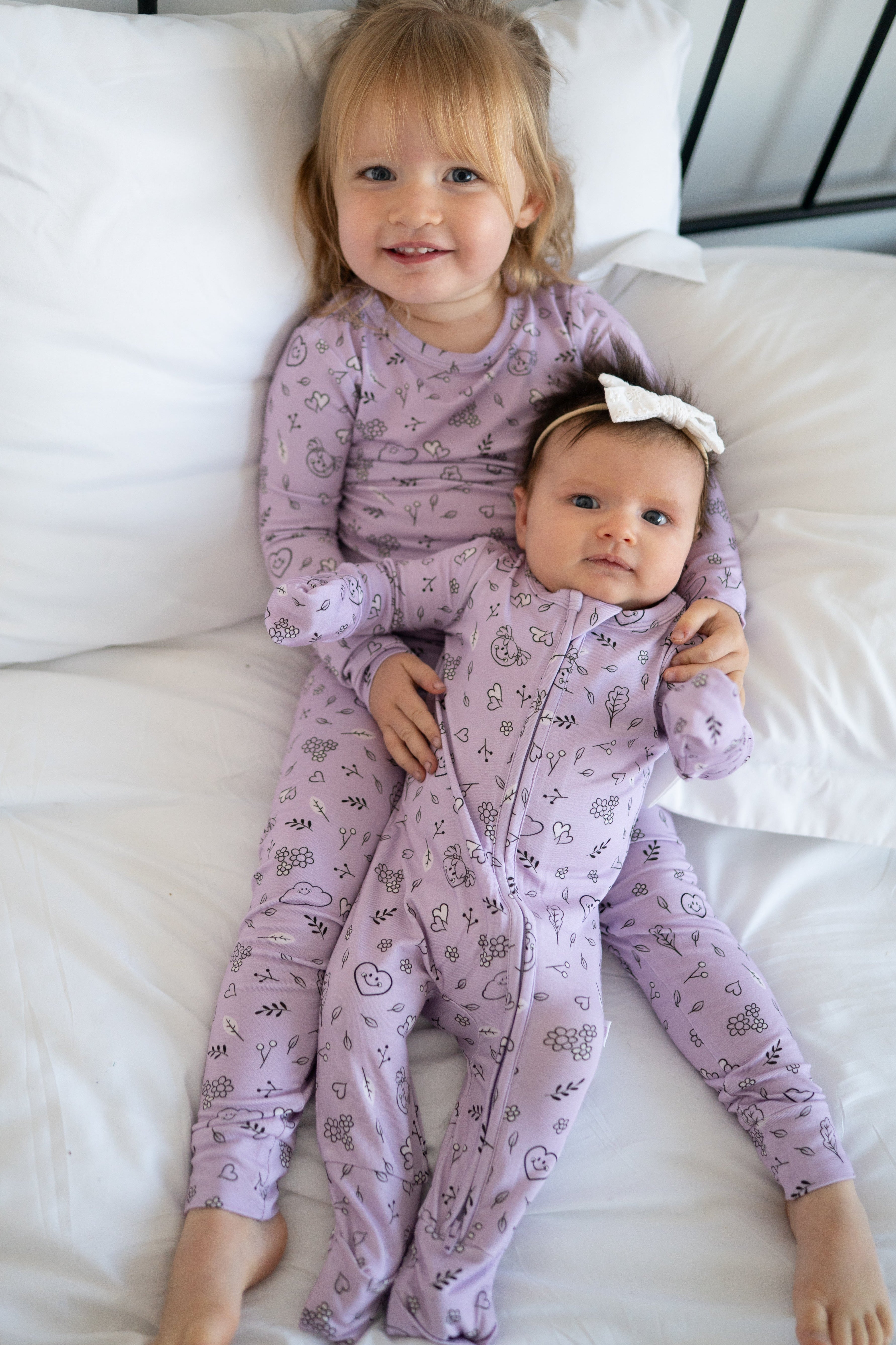 Two children in lilac pajamas with a doodle print.