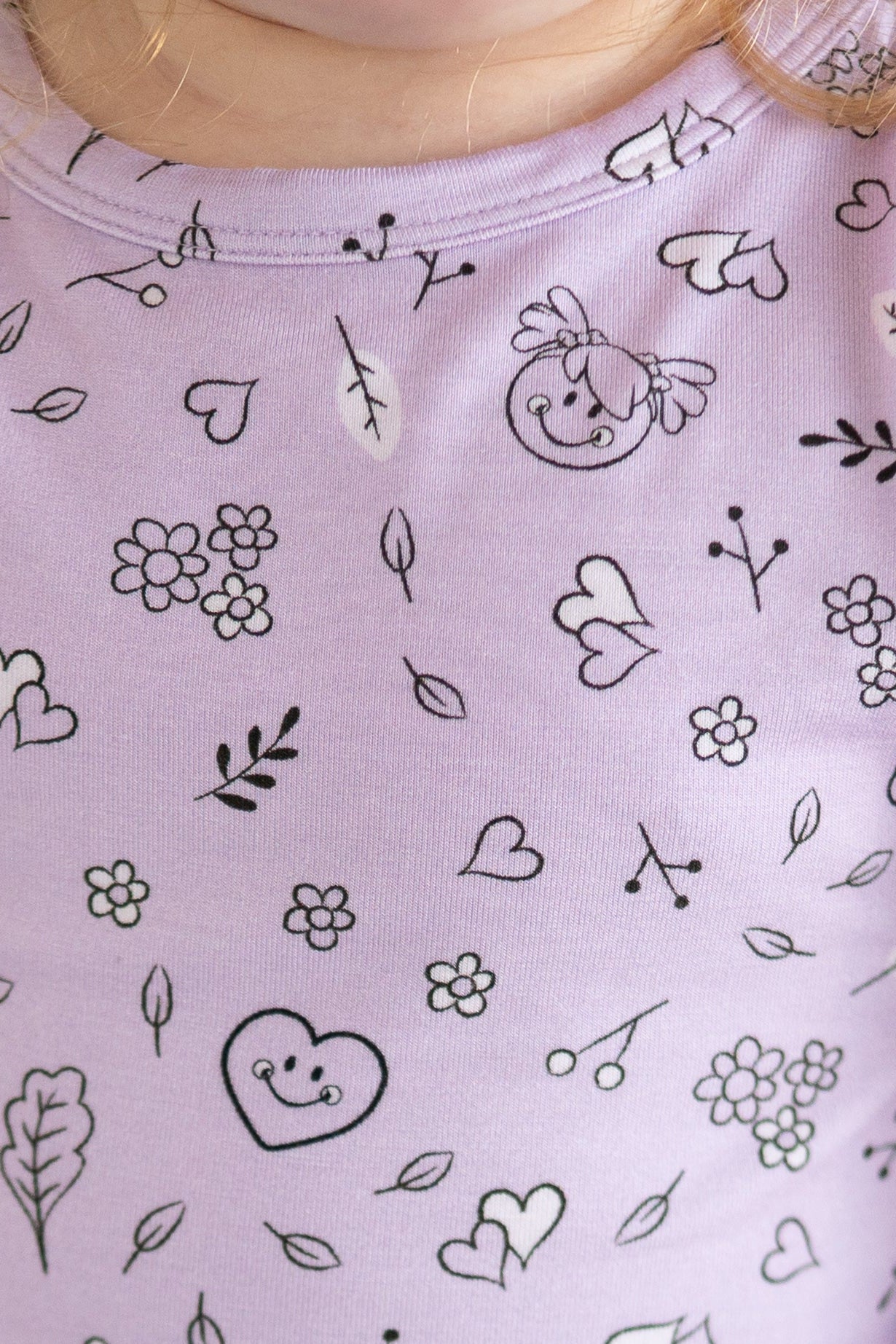 Lilac pajama set with a repeating pattern of hearts, flowers, leaves, and smiley faces.