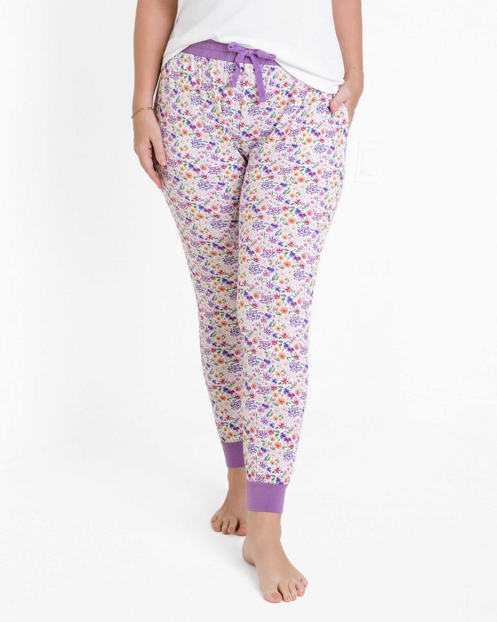 Women's white joggers with a purple floral print and purple cuffs.