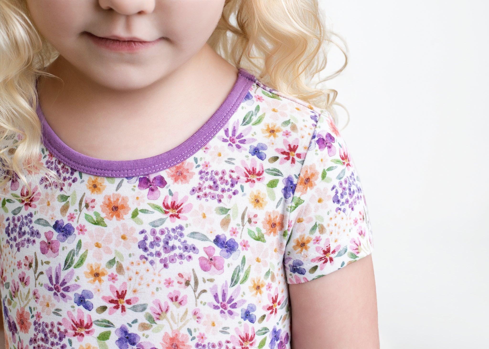 A child's floral print dress with a purple neckline.