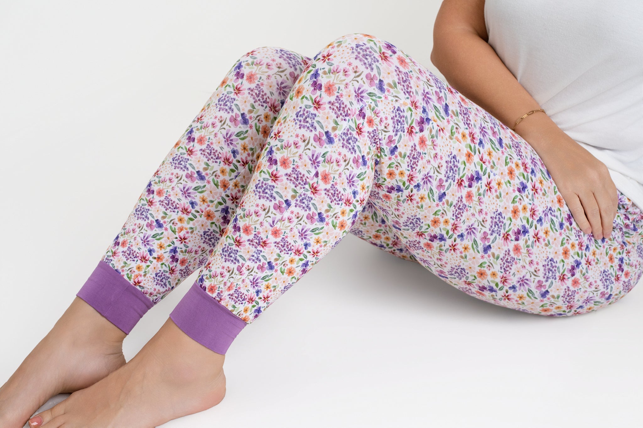 Women's white joggers with a dainty floral print and purple cuffs.