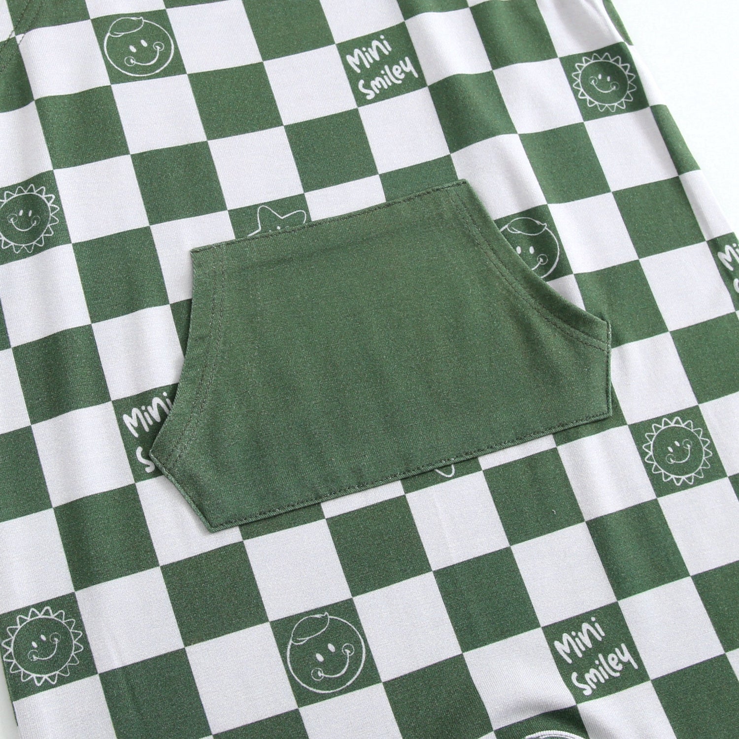 Green and white checkered overalls with smiley face prints and a front pocket.