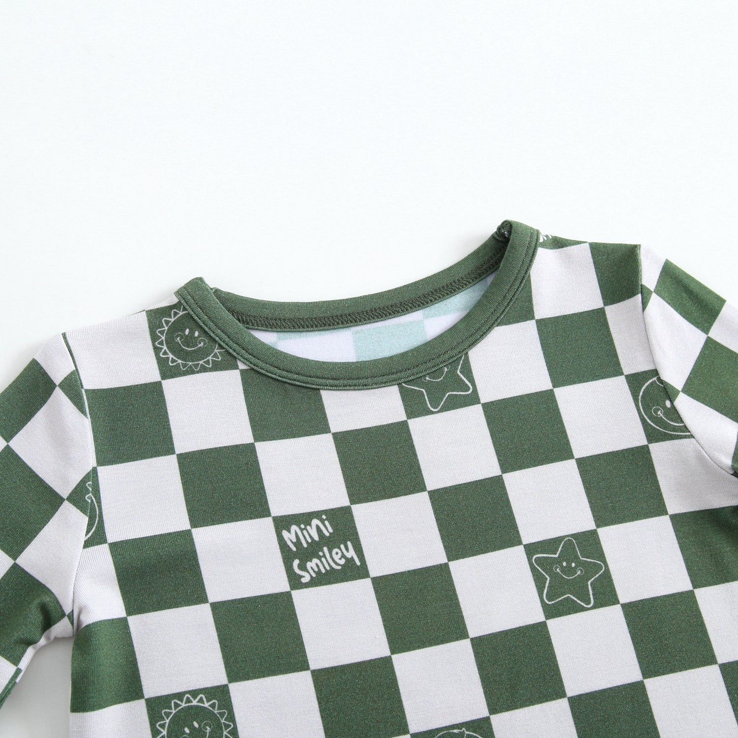 Green and white checkerboard pajama top with smiley sun and star graphics.
