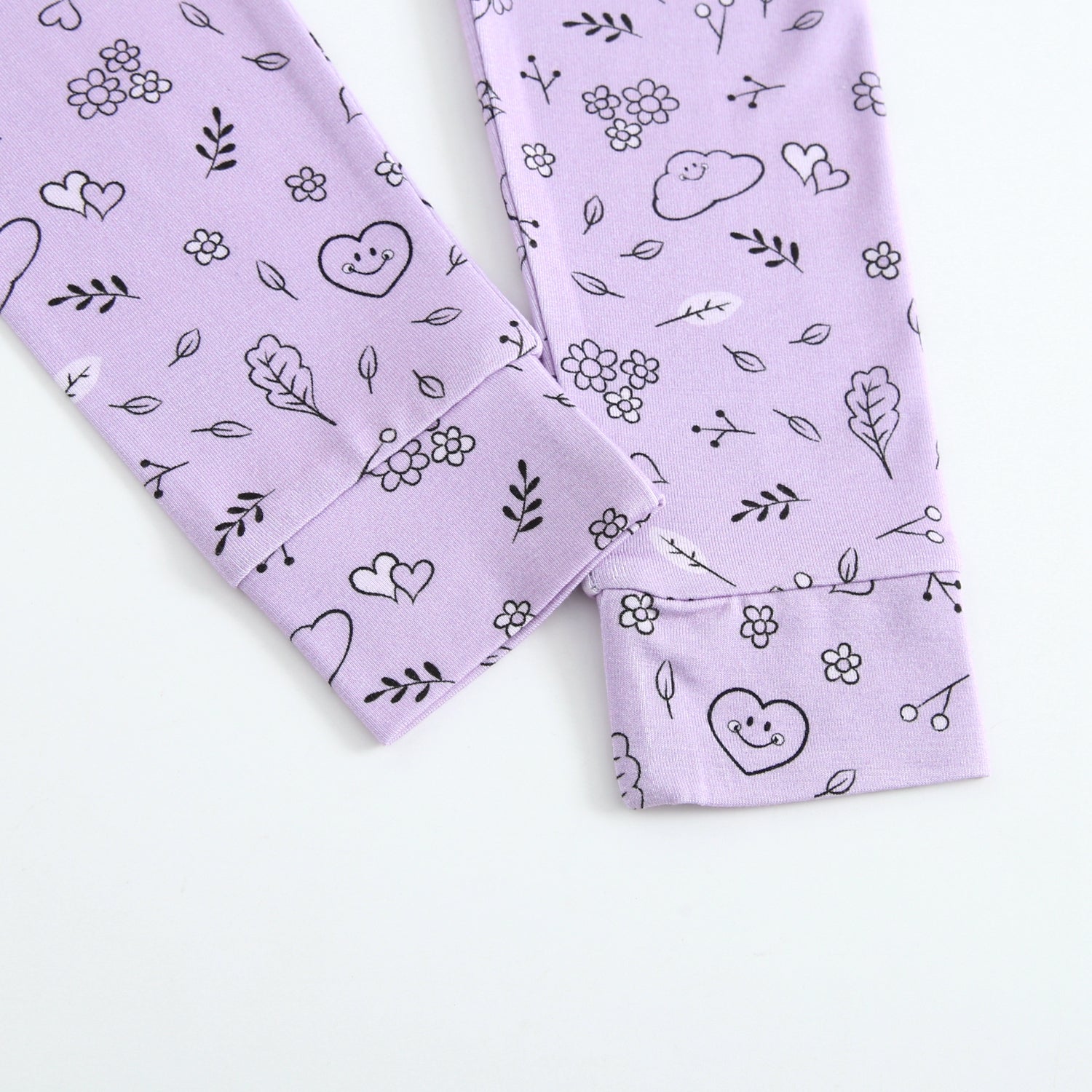 Purple pajama set with a lilac doodle print featuring smiley faces and flowers.