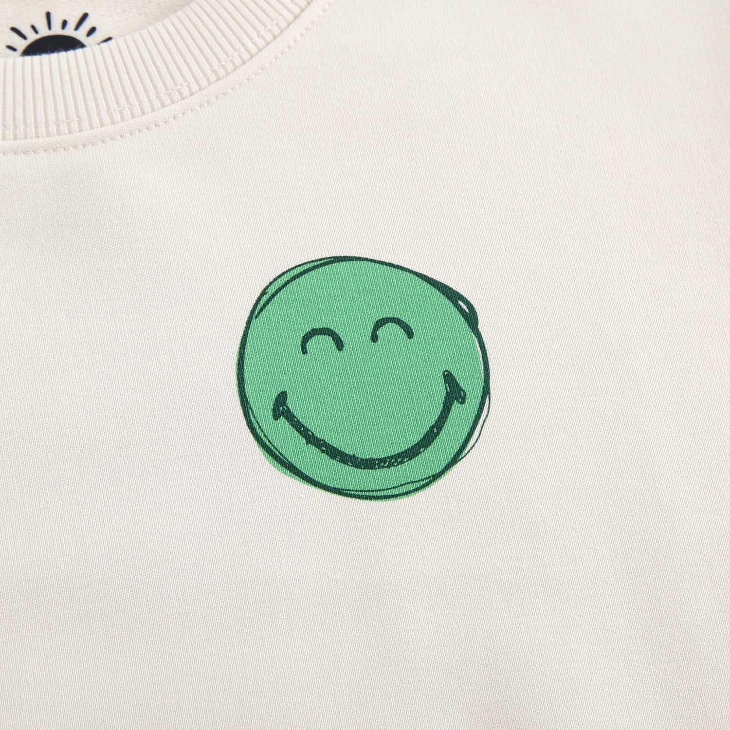Cream crewneck sweatshirt with a green smiley face graphic.
