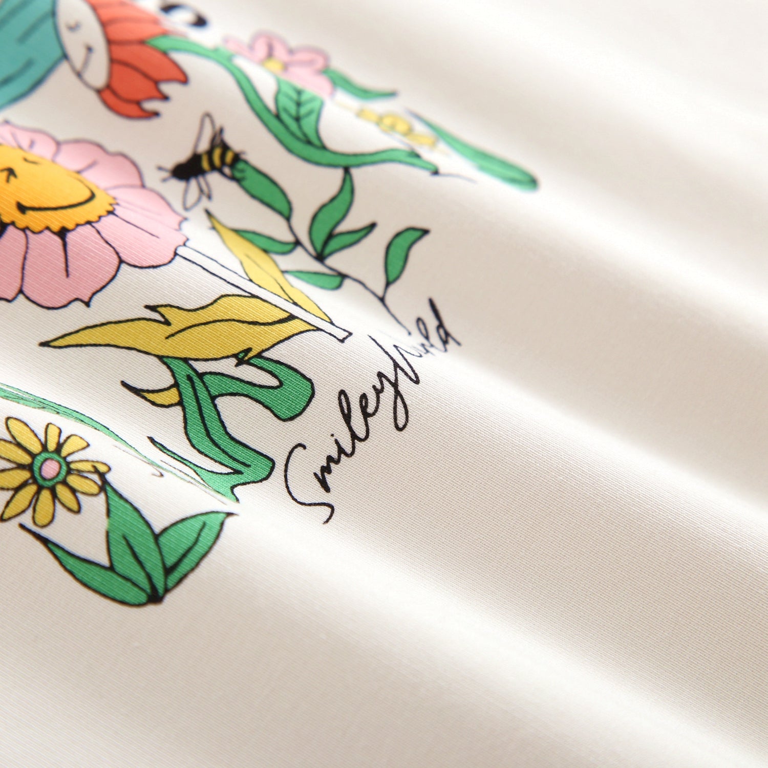 Cream crewneck with SmileyWorld® flower and bee graphic.