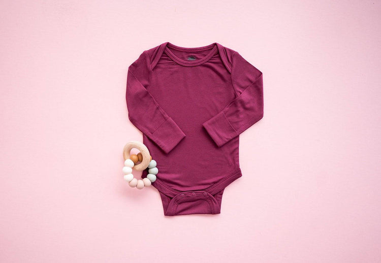 Close-up of the Long Sleeve Bamboo Bodysuit in Burgundy with a neutral backdrop
