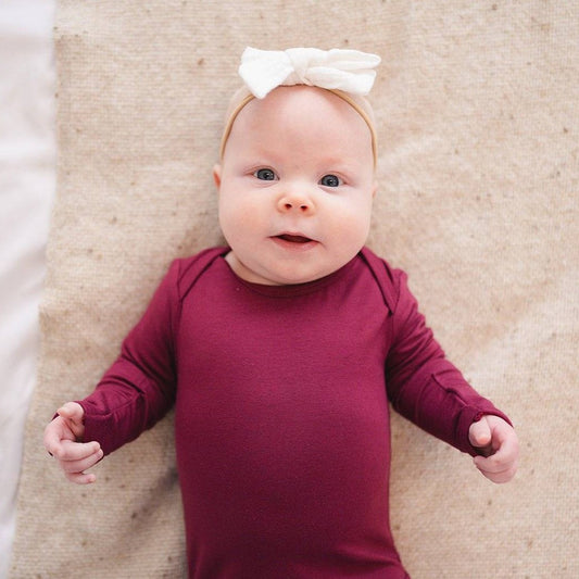 Close-up of the Long Sleeve Bamboo Bodysuit in Burgundy with a neutral backdrop