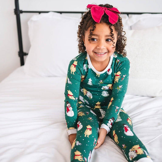 A child lying on a bed wearing the 'Snug Fit PJ Set - My Favourite Day' with a snowman design